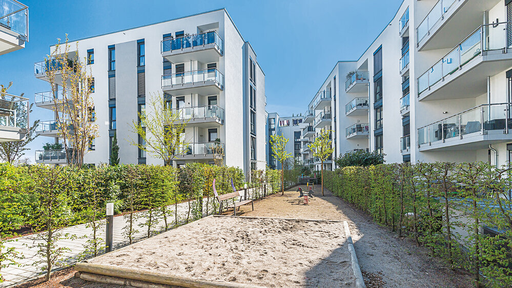 Wohngebäude am Mainzer Rheinufer mit begrüntem Innenbereich, Spielbereich, Balkonen und hellen Fassaden